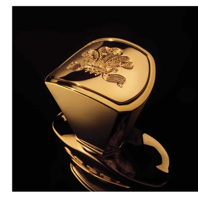 A shiny golden bottle cap with an embossed emblem featuring a crown and wings against a black background.