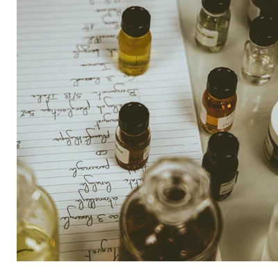 Hand holding a glass perfume bottle with amber liquid and a gold cap featuring the text Royal Princess Oud and CREED.