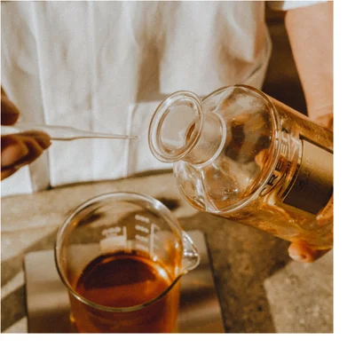 A pink rose is disintegrating with petals and particles flying outwards against a black background.