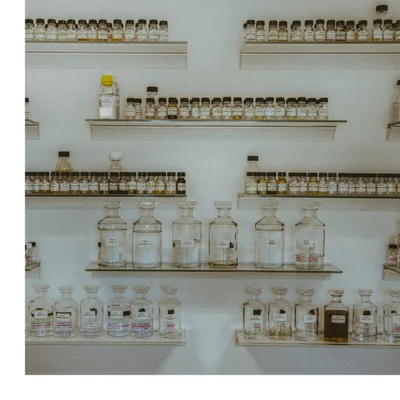 A red and clear perfume bottle with a gold cap is surrounded by a splash of water and ice fragments against a black background and shows the text Royal Princess Oud and CREED.