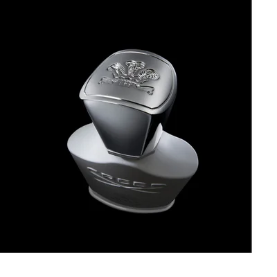 A light grey perfume bottle with a shiny silver cap featuring an embossed crest is shown against a dark background, with the words Creed Silver Mountain Water visible on the front.