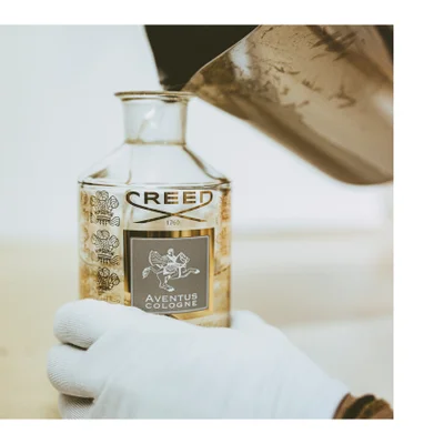 Liquid is poured from a bottle with the text CREE into a beaker containing dark liquid while a pipette is held above.