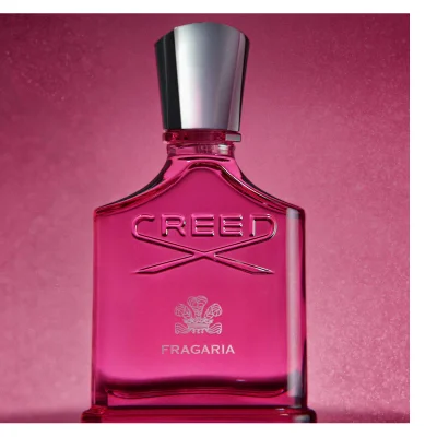 A pink Creed perfume bottle with a silver cap is shown on a pink background, with text CREED and FRAGARIA visible on the bottle.